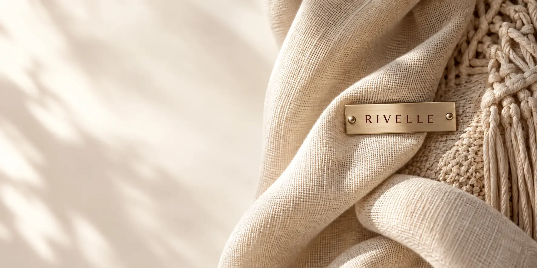 Ivory textile and an engraved Rivelle plaque in a quiet editorial composition